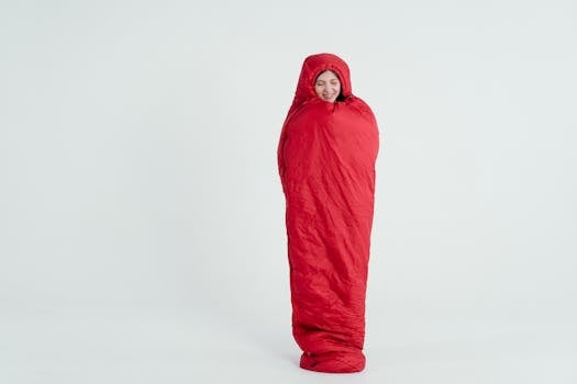 A young woman wrapped in a red sleeping bag, smiling with a serene expression.