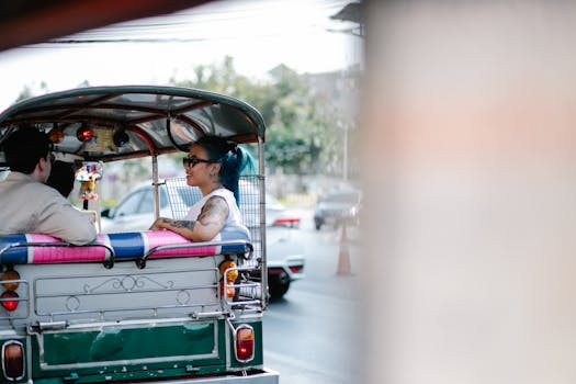 Couple enjoying a tuk-tuk ride on a bright day, capturing urban life and transportation.