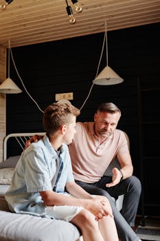 Father and son having a meaningful talk in a cozy bedroom setting.