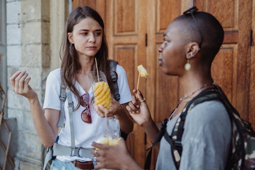 Two women enjoy fresh fruit snacks outdoors during their vacation, capturing a travel moment.