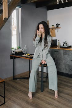 A woman enjoys a calming morning drink in a cozy kitchen, promoting relaxation and mindfulness.