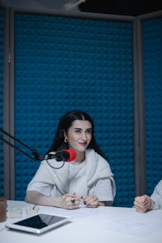 Woman recording a podcast in a soundproof studio, using a microphone.