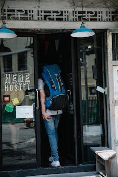A backpacker entering a hostel through a glass door, featuring travel ambiance.
