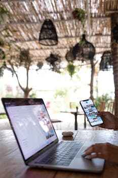 A person uses a laptop and smartphone in a Bali outdoor café, embracing the digital nomad lifestyle.