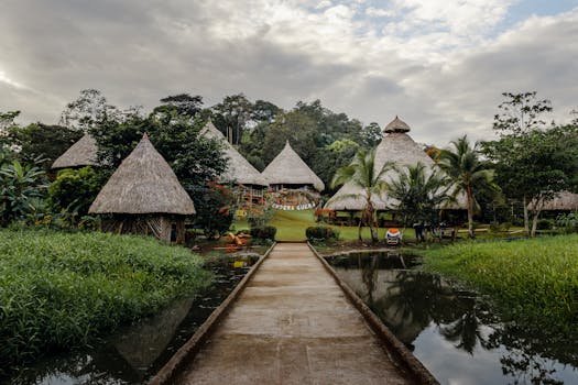 Explore the peaceful retreat of a tropical village with thatched roof huts surrounded by lush greenery and water.
