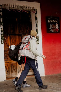Two travelers with backpacks walking by a quaint shopfront on a historic street.